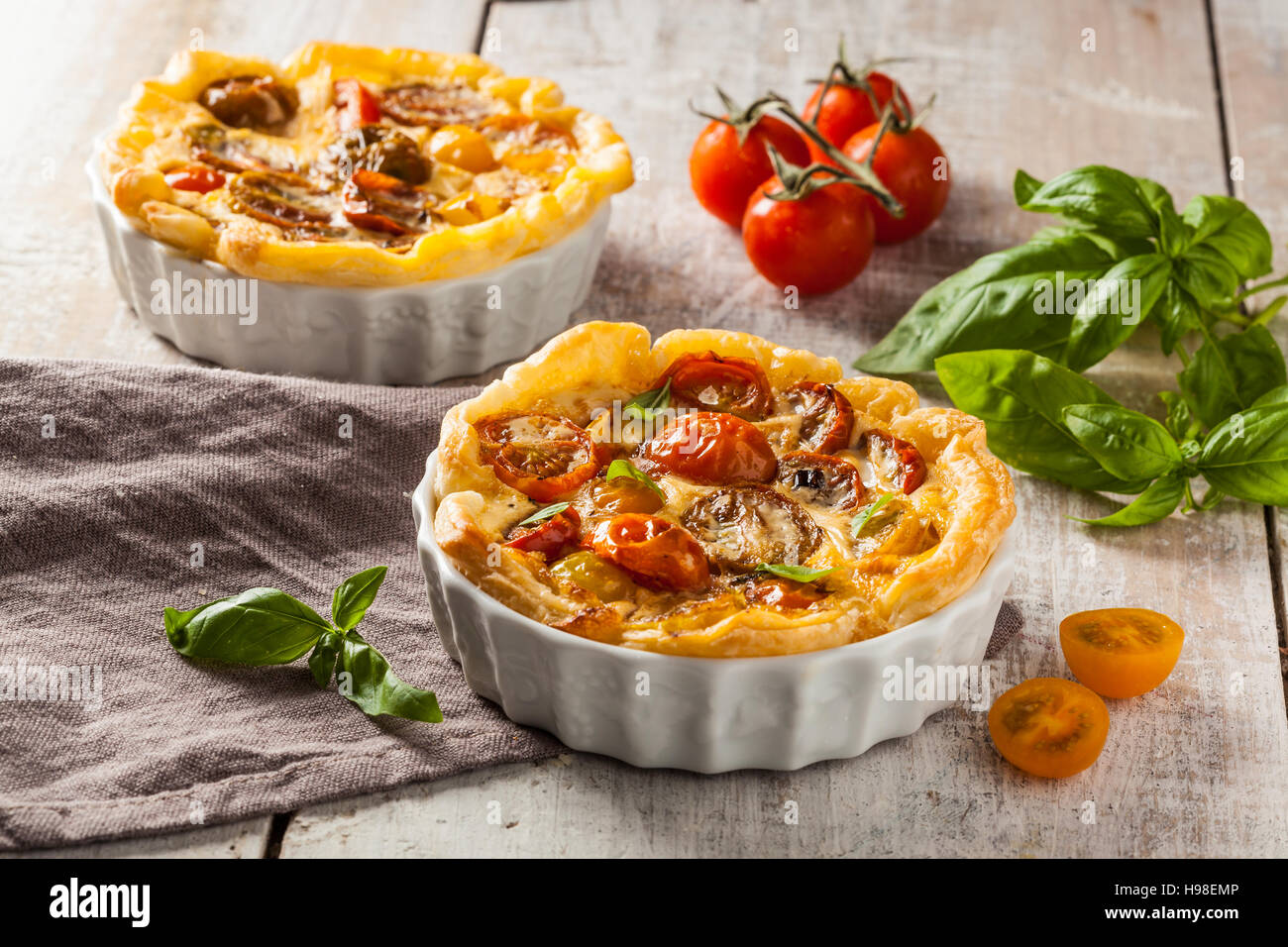 Quiche aux tomates cerises sur une table en bois rustique. Banque D'Images