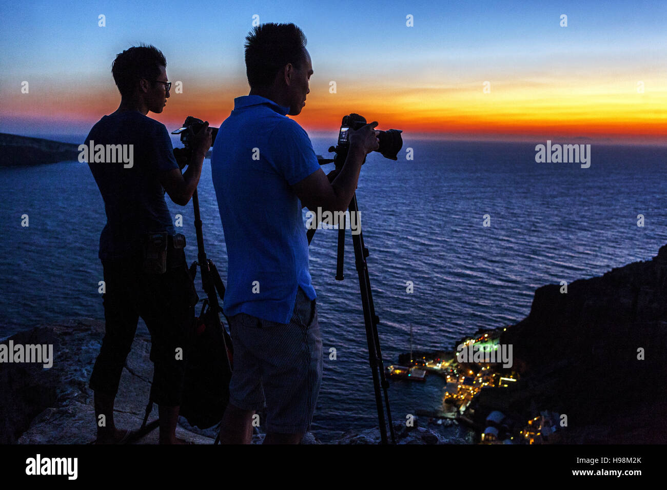 Deux photographes avec un trépied photographiant le coucher du soleil dans le village d'Oia, Santorin, coucher du soleil en Grèce Banque D'Images
