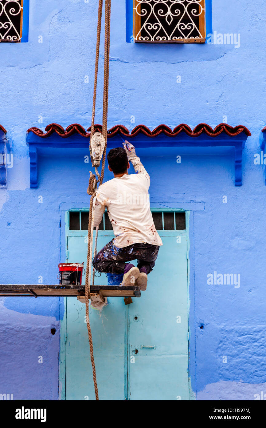 Un homme peint l'extérieur d'une maison traditionnelle en bleu, la médina, Chefchaouen, Maroc Banque D'Images