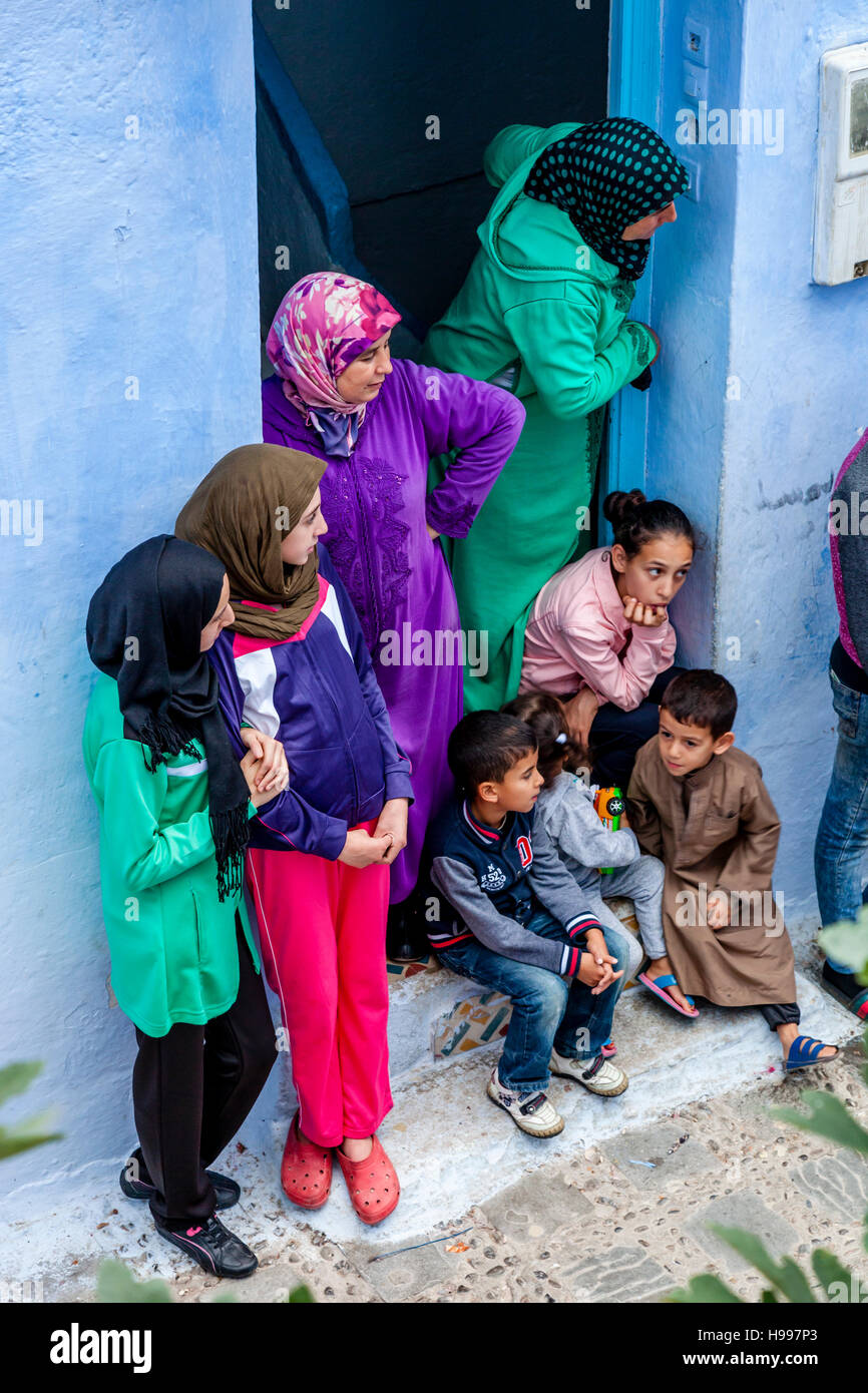 Une famille marocaine à regarder la vie dans leur face de leur porte avant, Chefchaouen, Maroc Banque D'Images