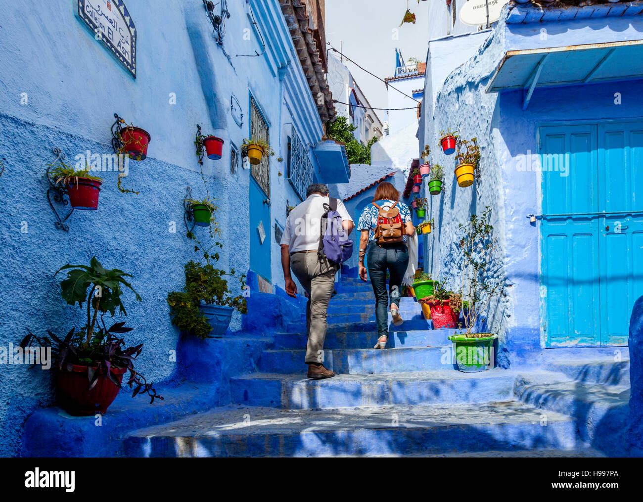 Deux touristes à monter une rue colorée dans la médina, Chefchaouen, Maroc Banque D'Images