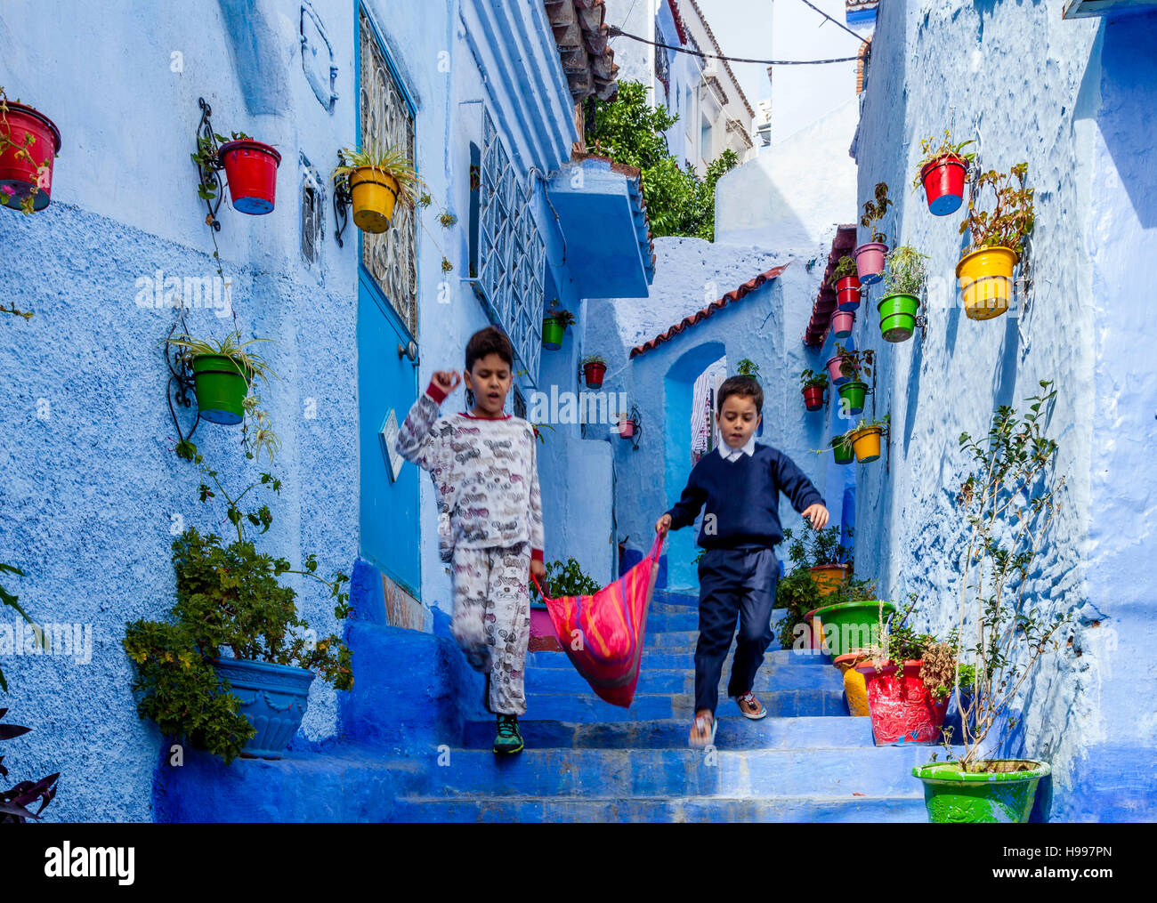 Deux garçons portant un sac, une rue pittoresque de la médina, Chefchaouen, Maroc Banque D'Images