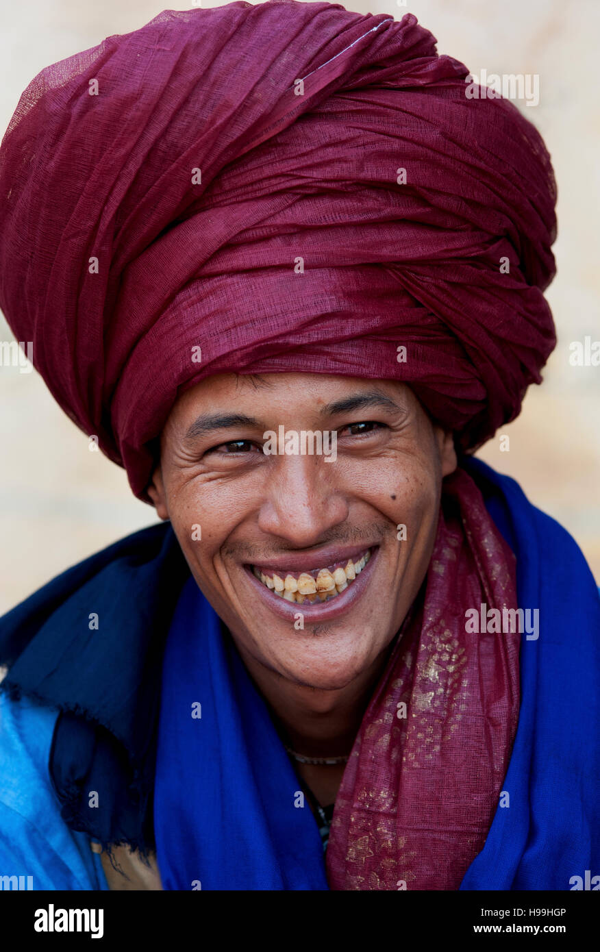 Portrait de nomade bédouine avec turban écarlate et un grand sourire de vendre ses marchandises en destination touristique populaire Ait Benhaddou, Maroc. Banque D'Images