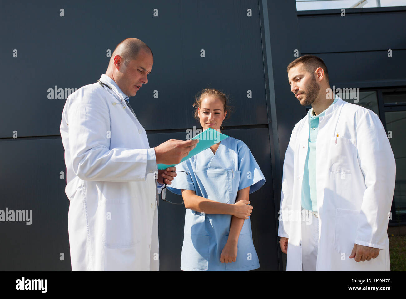 Groupe de médecins à la recherche de dossier médical à l'extérieur Banque D'Images Groupe de médecins à la recherche de dossier médical à l'extérieur Banque D'Images