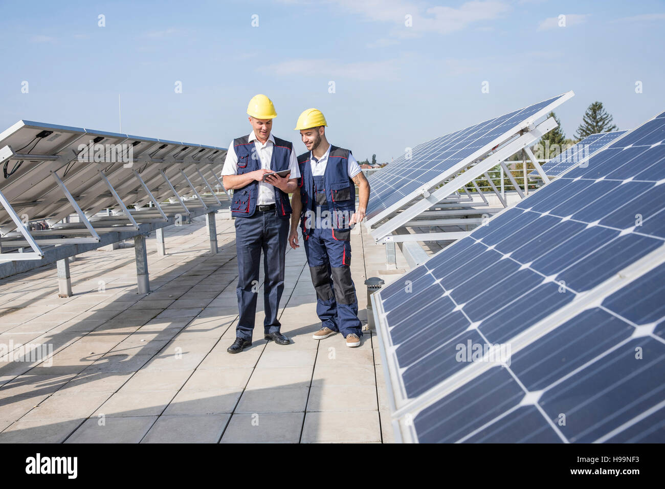 Les travailleurs de la construction à côté des panneaux solaires looking at digital tablet Banque D'Images