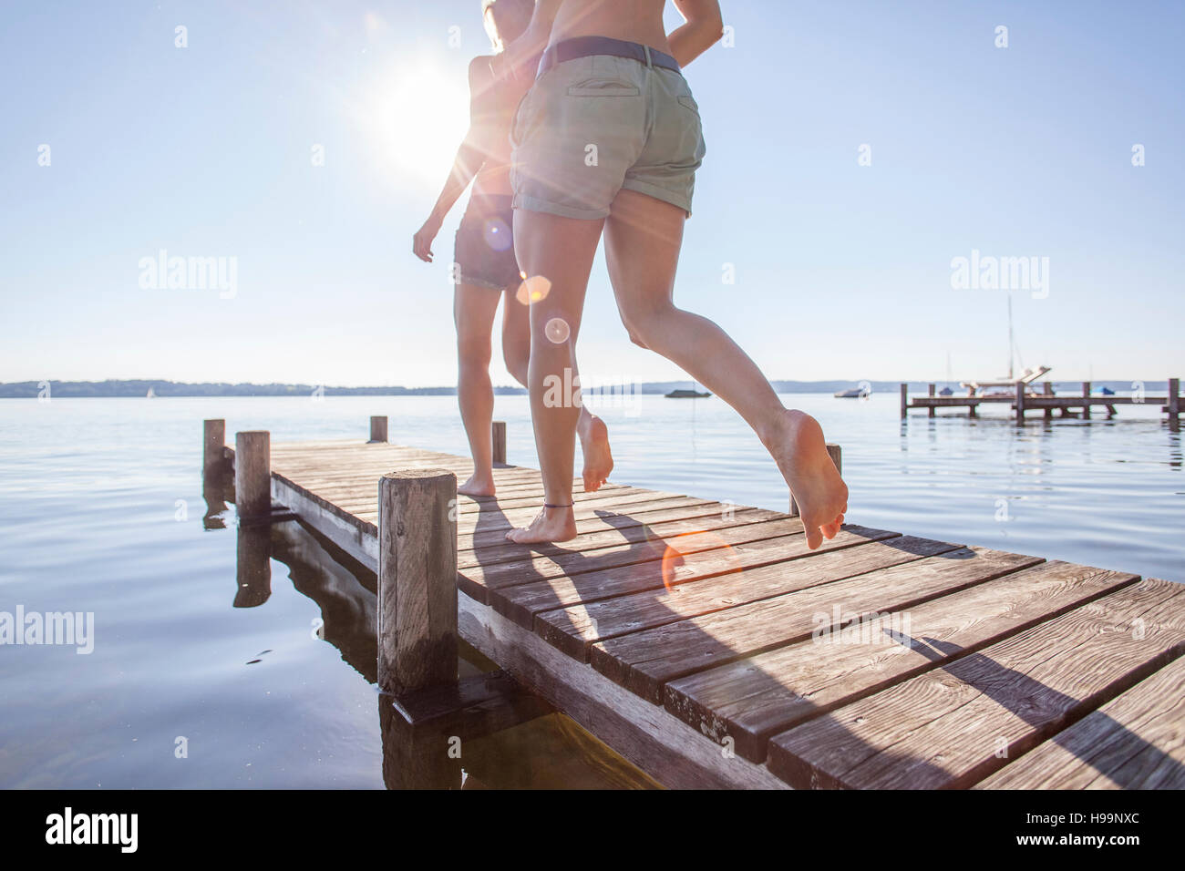 Deux jeunes femmes s'exécutant sur pier by lake Banque D'Images