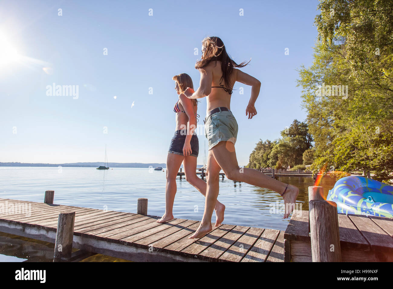 Deux jeunes femmes s'exécutant sur pier by lake Banque D'Images