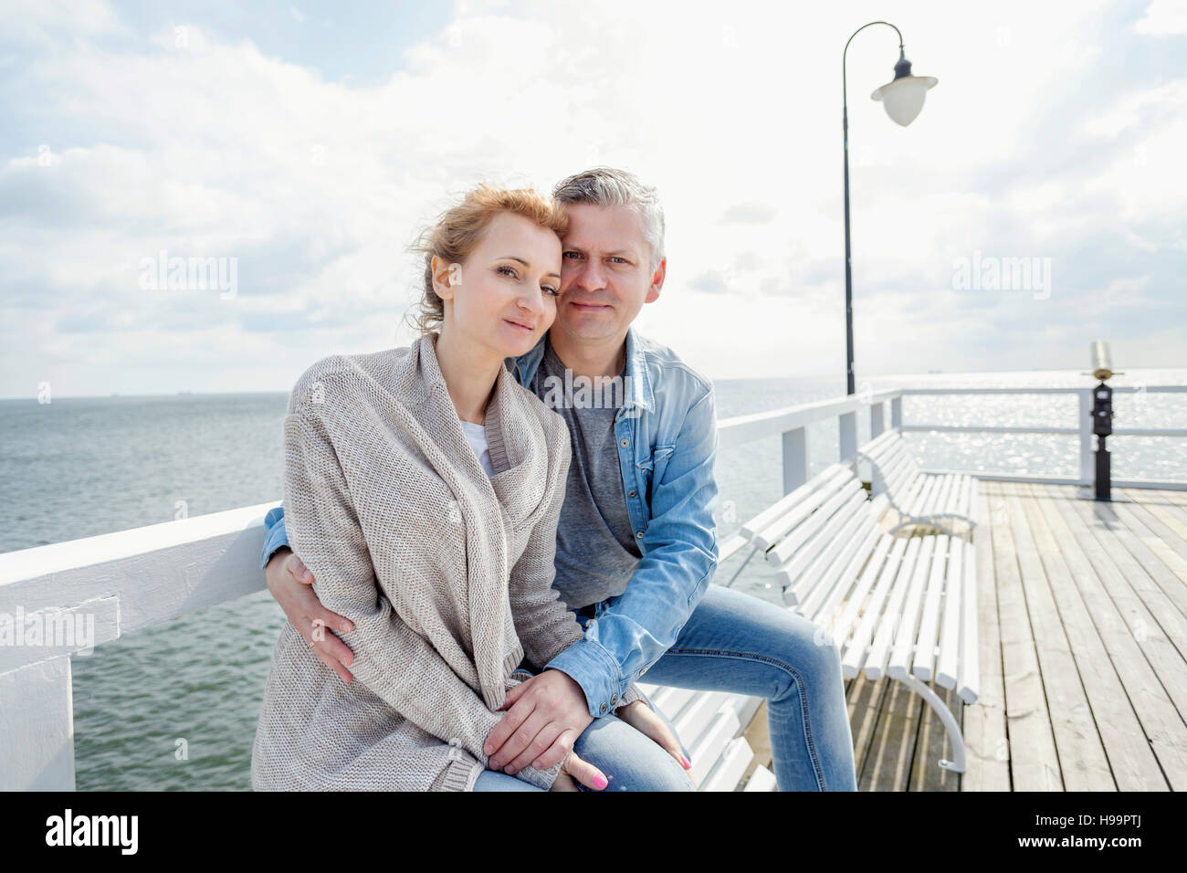 Couple in love sitting on jetty Banque D'Images
