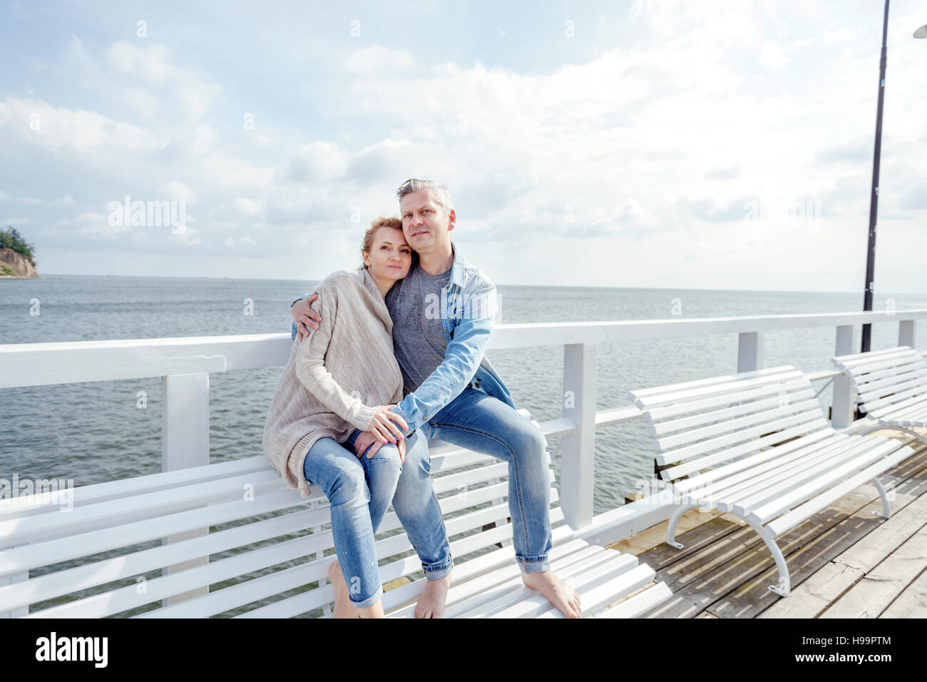 Couple in love sitting on jetty Banque D'Images