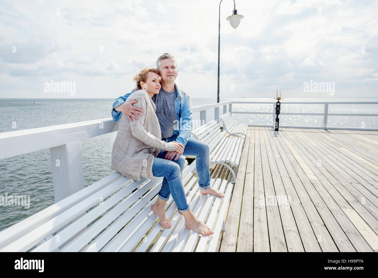 Couple in love sitting on jetty Banque D'Images