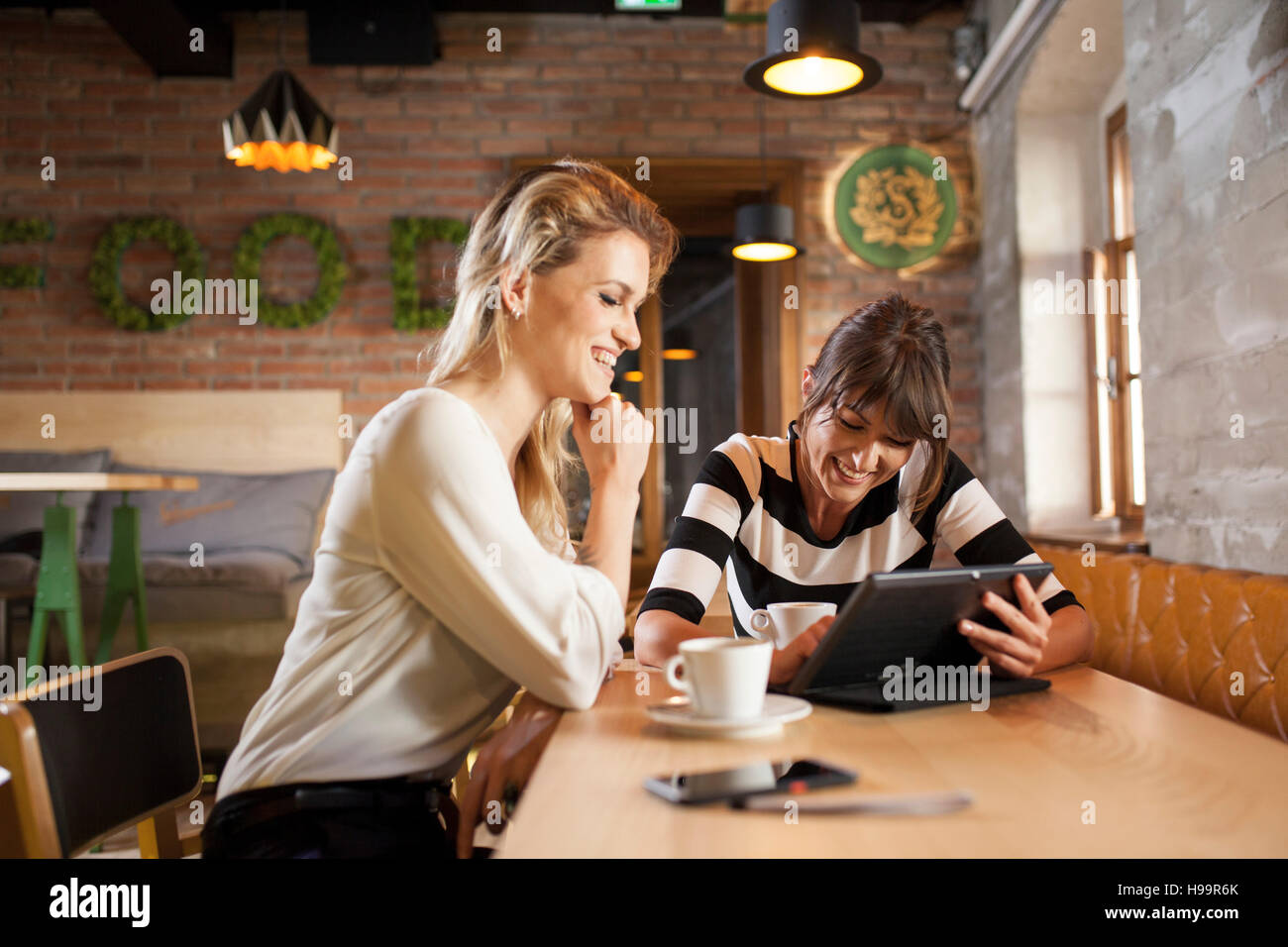 Deux copines using digital tablet in coffee shop Banque D'Images