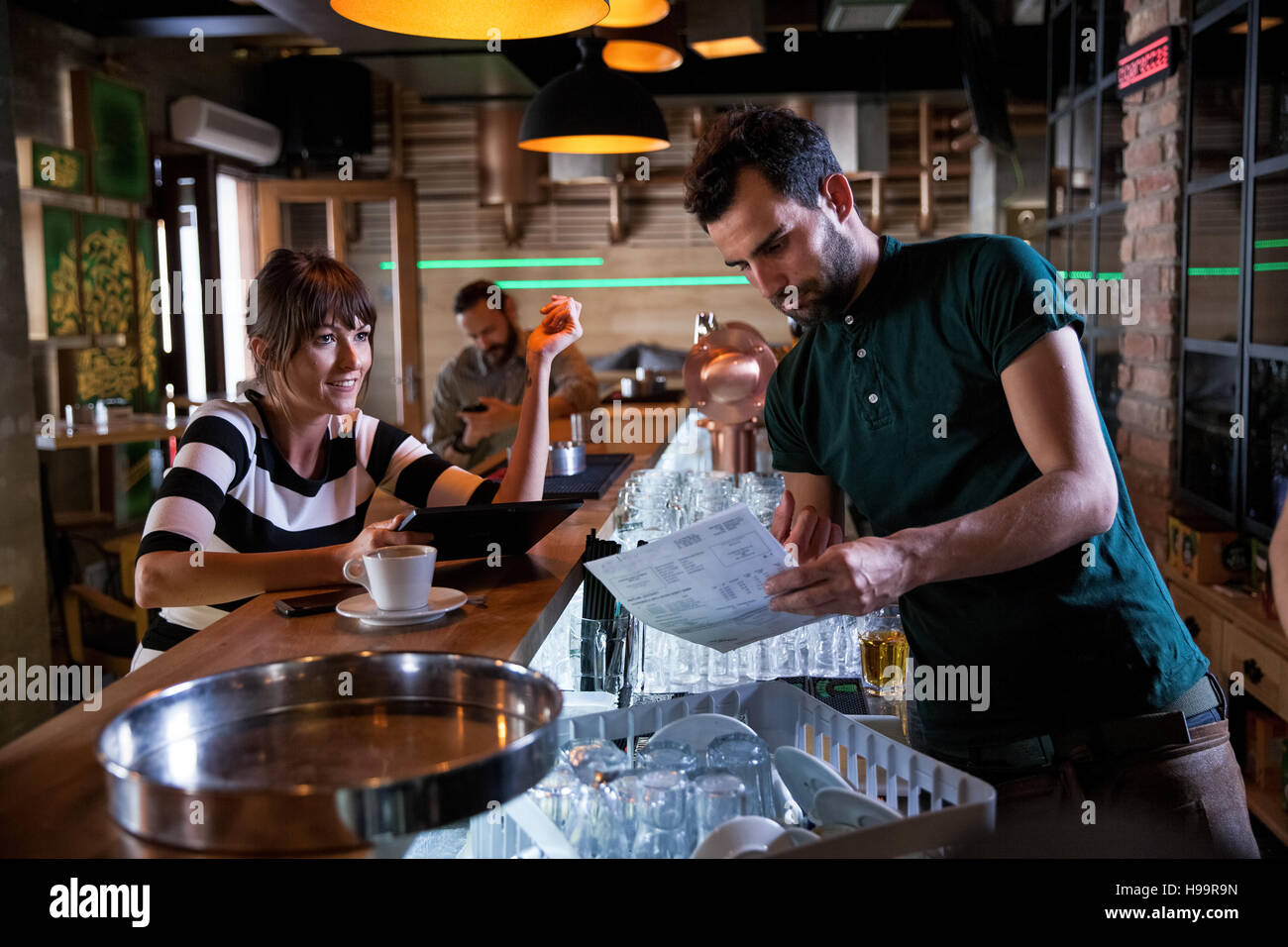 Femme au comptoir de café à parler de barman Banque D'Images