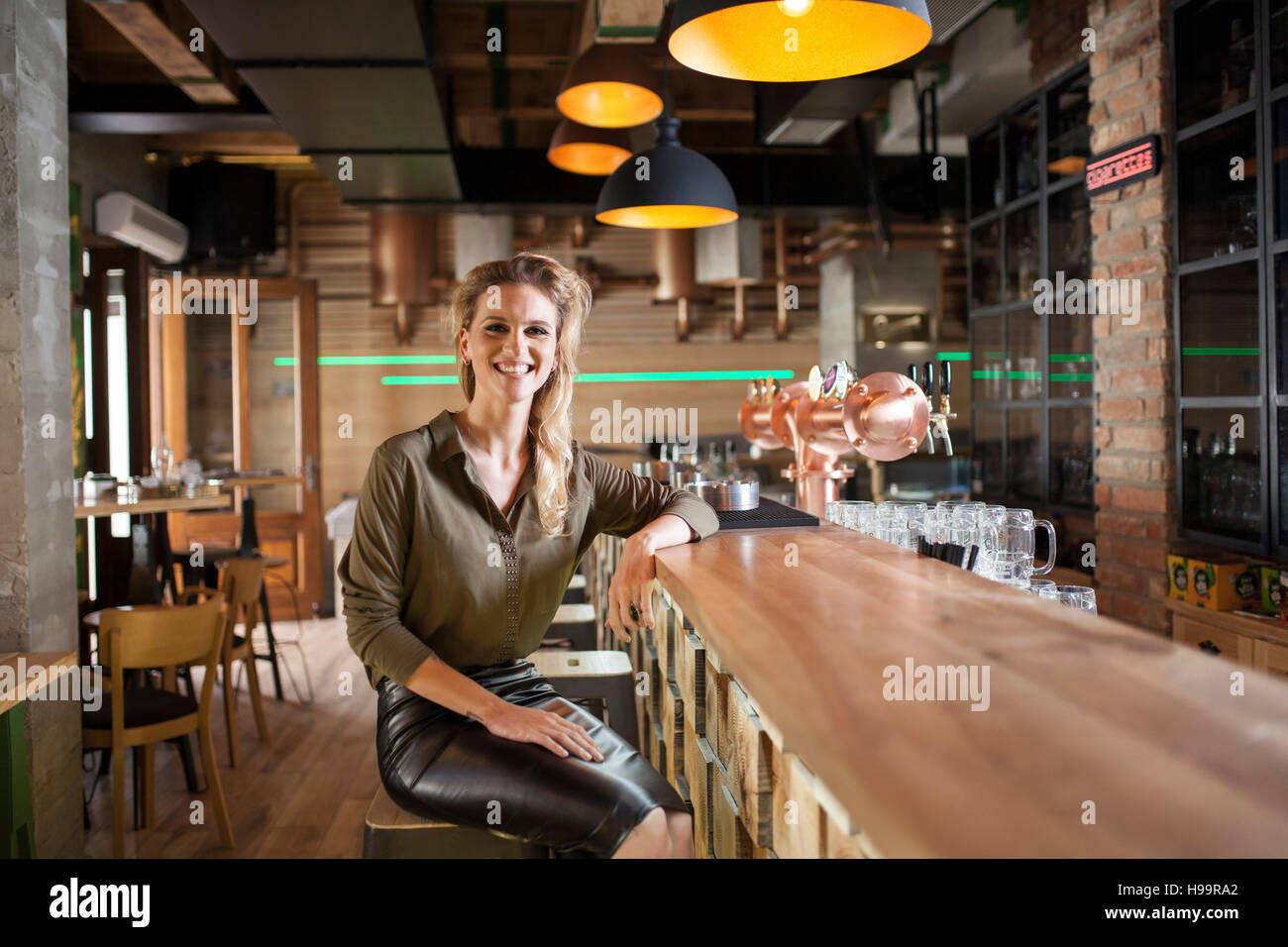 Femme aux cheveux blonds assis au comptoir du bar à café Banque D'Images