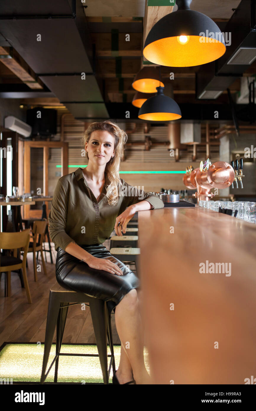 Femme aux cheveux blonds assis au comptoir du bar à café Banque D'Images