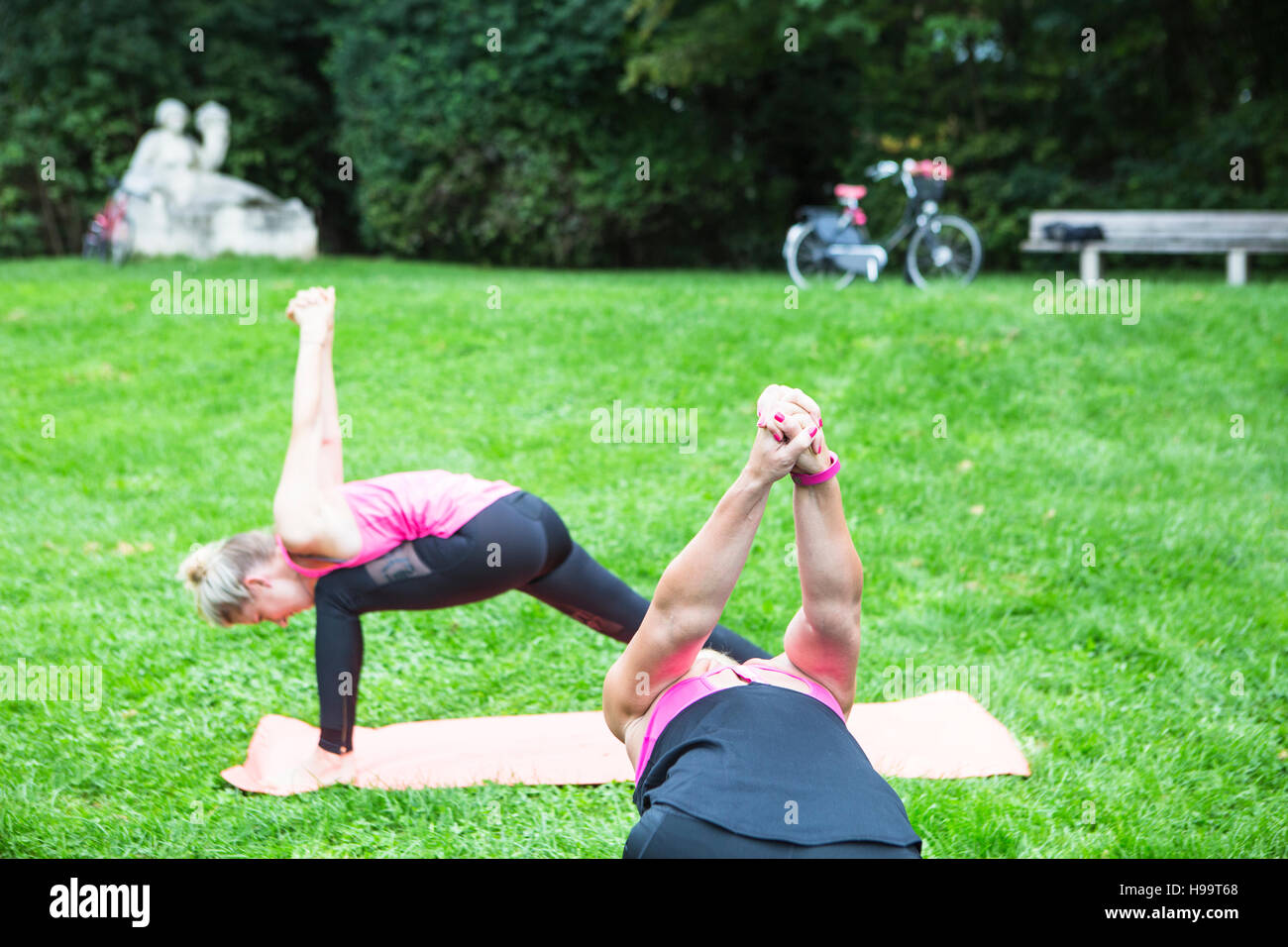 Les jeunes femmes pratiquant le yoga in park Banque D'Images