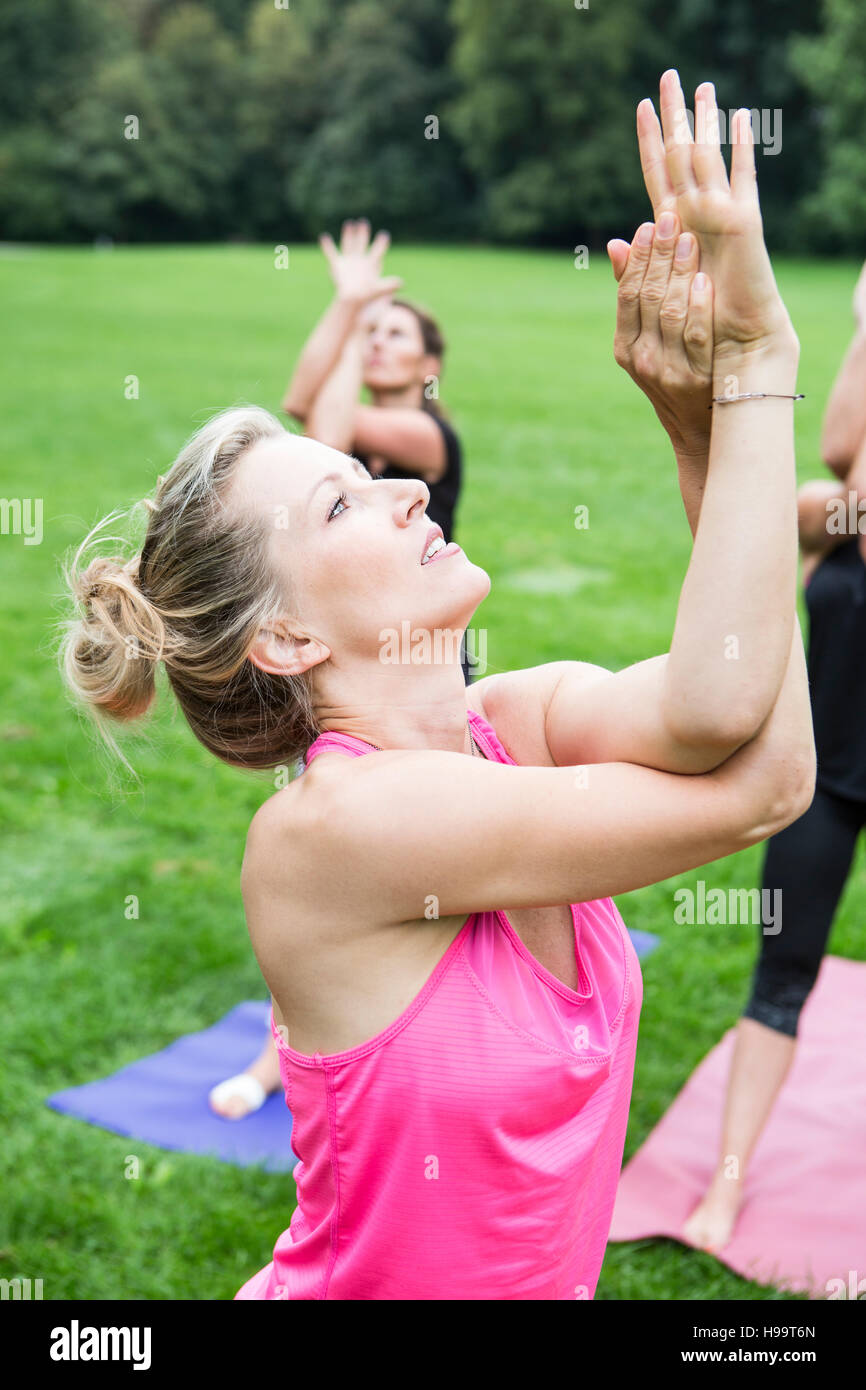 Les jeunes femmes pratiquant le yoga in park Banque D'Images