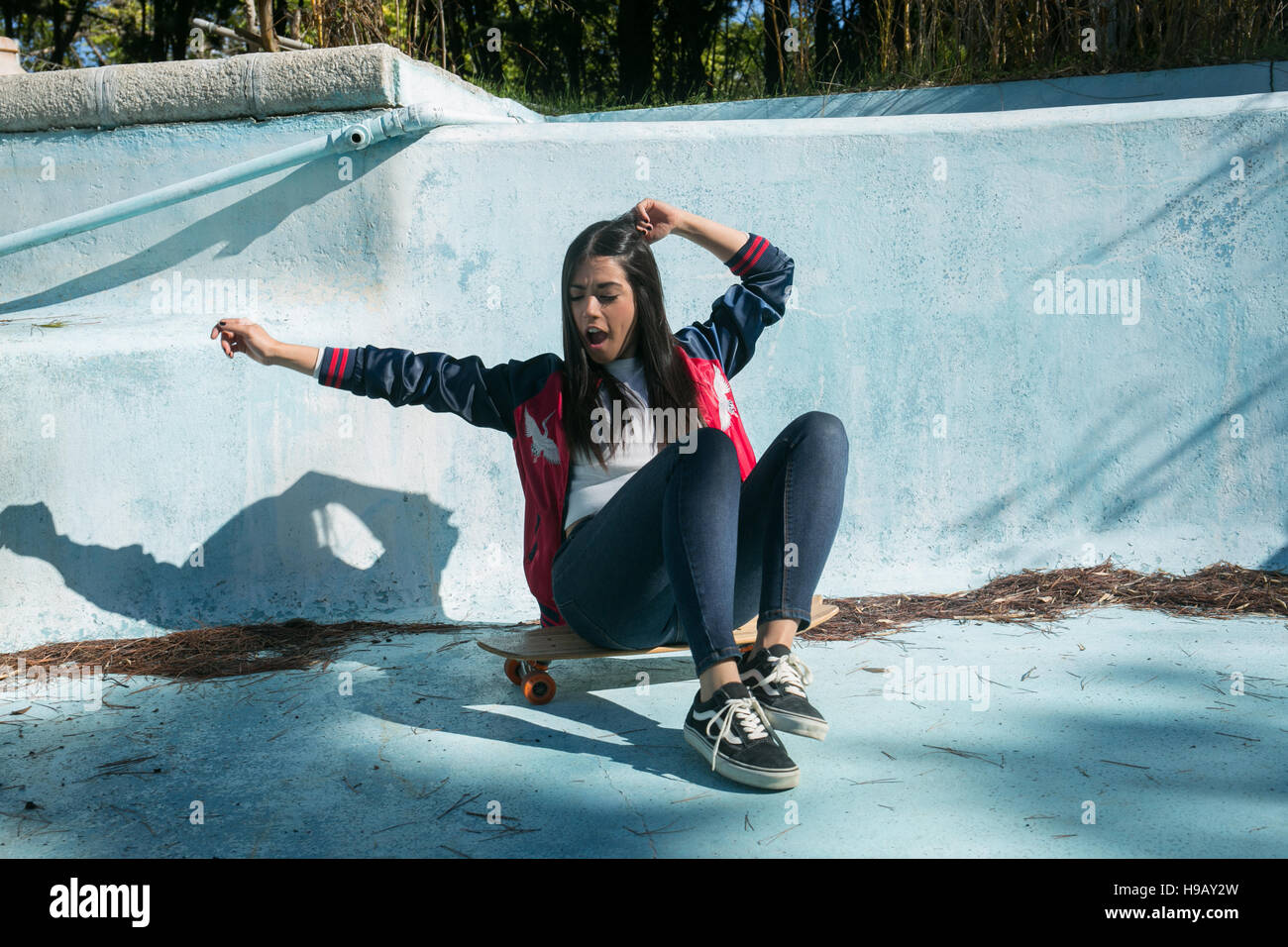 Jeune fille dans une piscine avec un skate et couleur style casual Banque D'Images