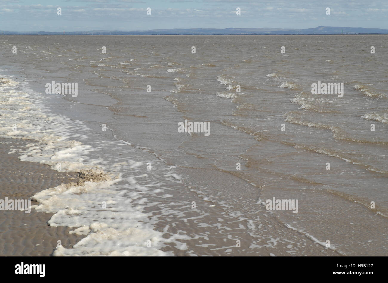 Écume de mer sur la plage de sable des vagues déferlantes vague canal de la rivière Ribble Estuary, à l'Ouest Pennines, Fairhaven, UK Banque D'Images