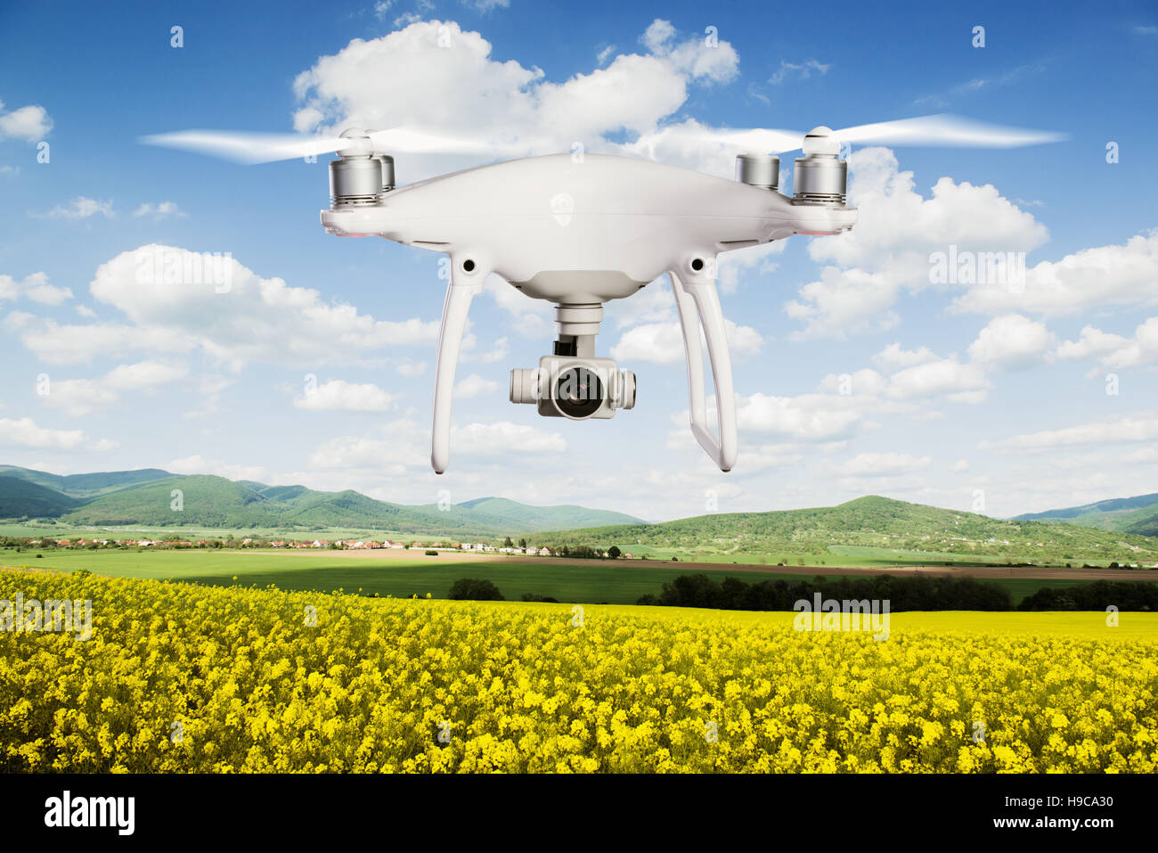 Drone planant à prendre des photos de champ de canola et Green Hills Banque D'Images