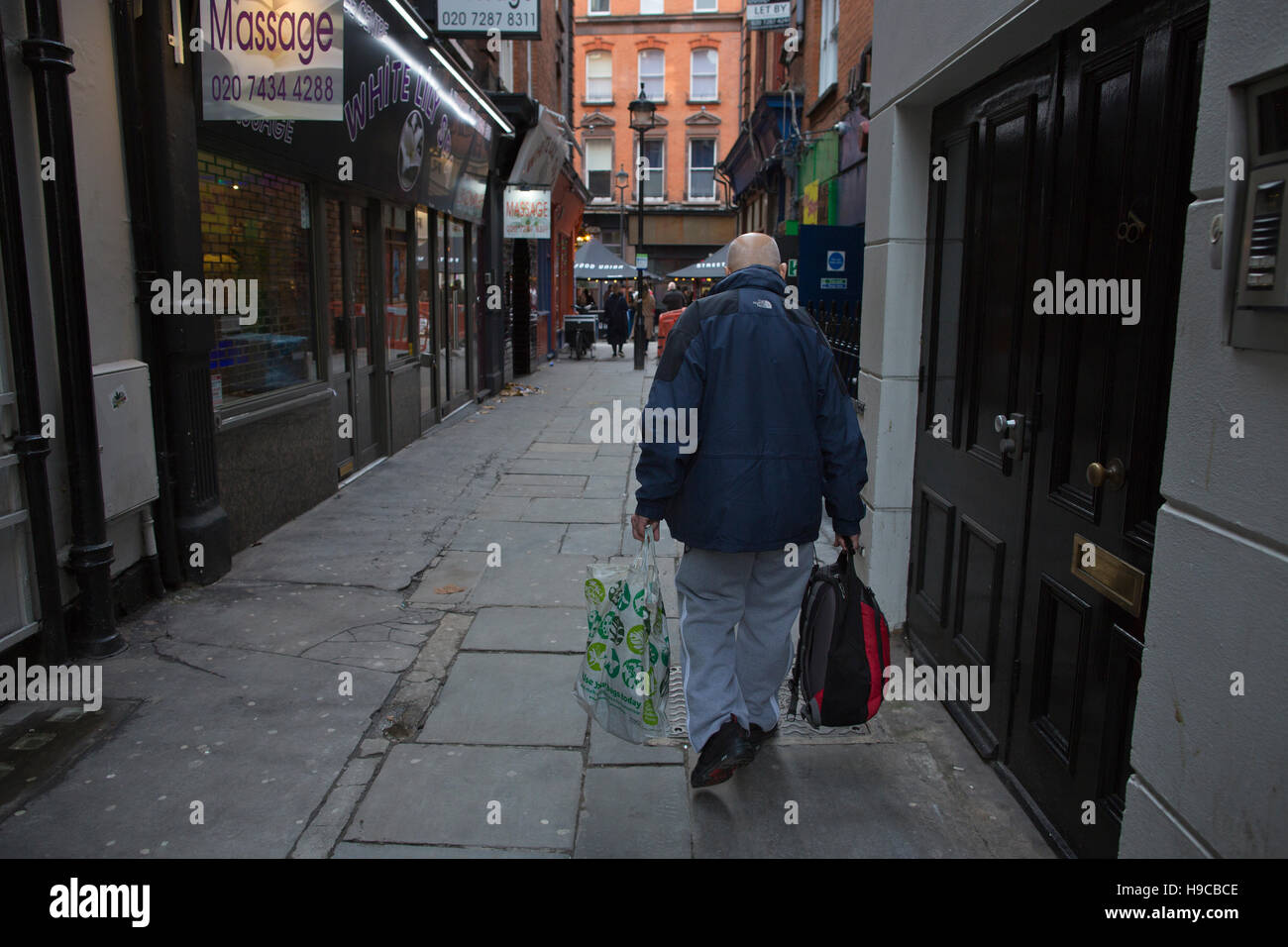 Homme marchant dans la journée vers le bas de la Cour, Tisbury au cœur de Soho, quartier rouge et peep show, Londres, Angleterre, Royaume-Uni Banque D'Images