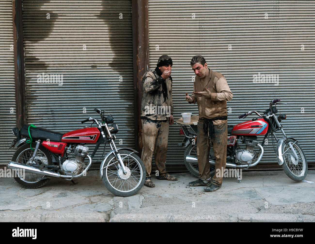Deux hommes musulmans chiites iraniens mangent leurs petits déjeuners après frottement de la boue sur leurs corps tôt le matin du jour de ashoura, la province du Lorestan, Khorramaba Banque D'Images