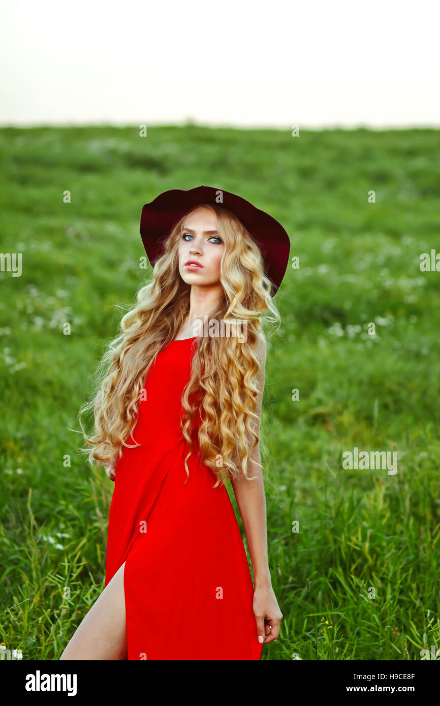 Belle jeune fille dans une robe rouge et red hat dans le domaine, sur un fond vert Banque D'Images