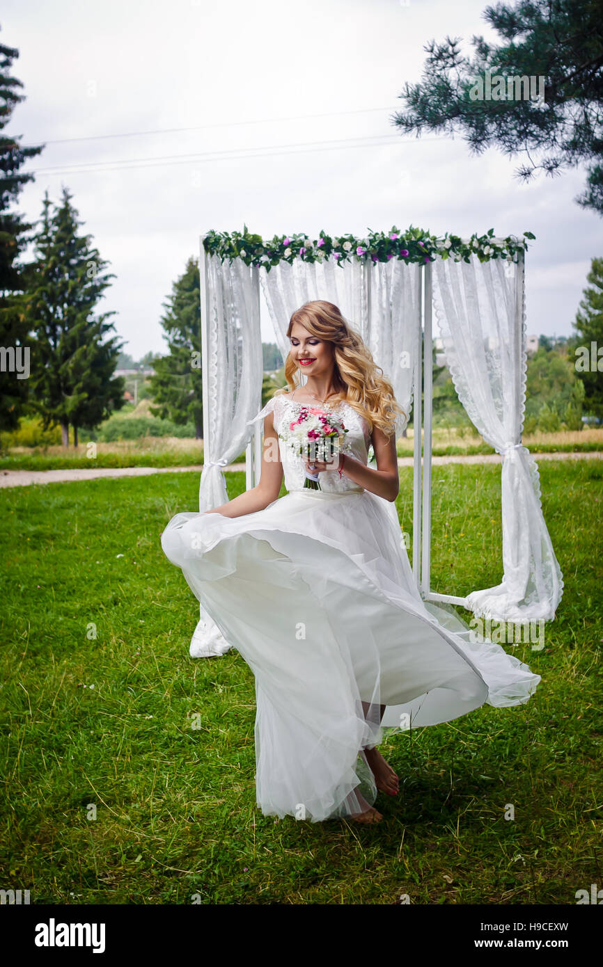 Belle blonde mariée dans une robe de mariée blanche tourne avec une robe à  la main, robe en mouvement, n'a pas l'air dans l'appareil photo Photo Stock  - Alamy