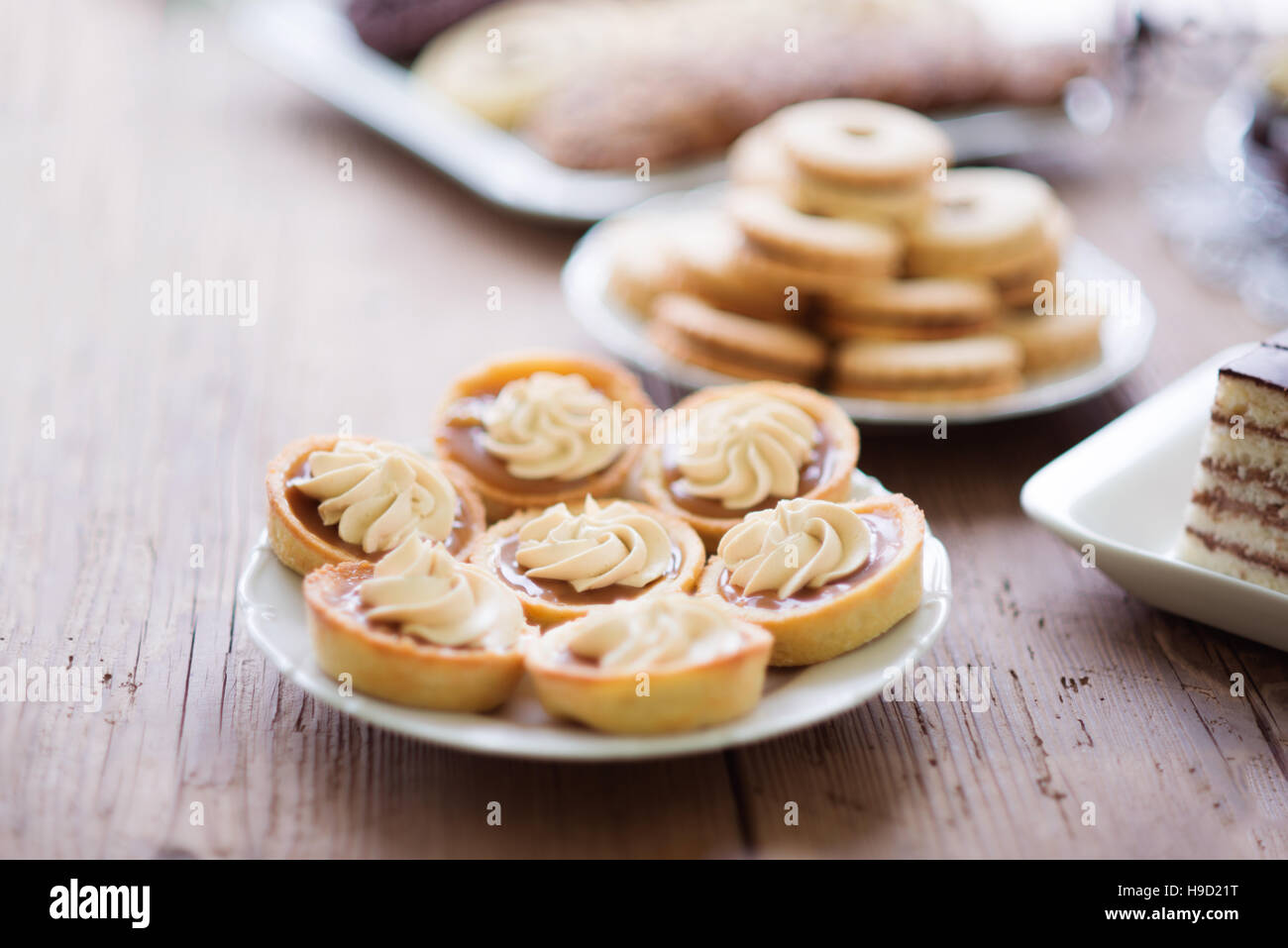 Table avec des tartelettes à la confiture et de la crème, fond de bois. Banque D'Images