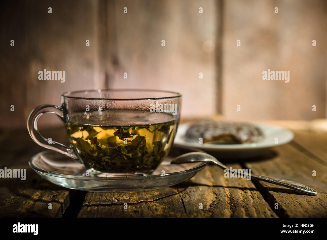 Tasse en verre de thé vert, cuillère à café et gâteau au miel sur table en bois Banque D'Images