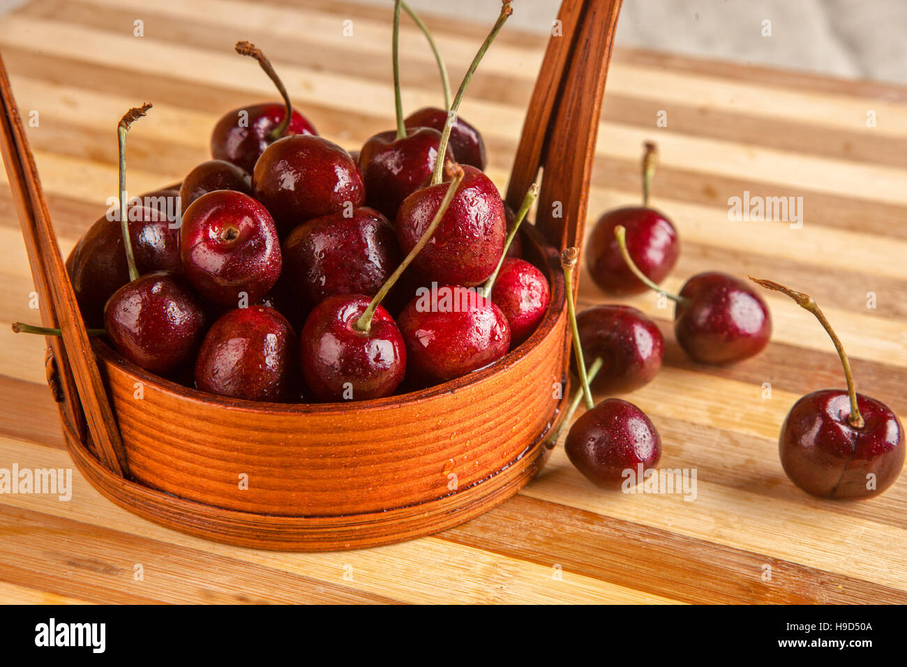 Cerises fraîches dans un panier sur la table Banque D'Images