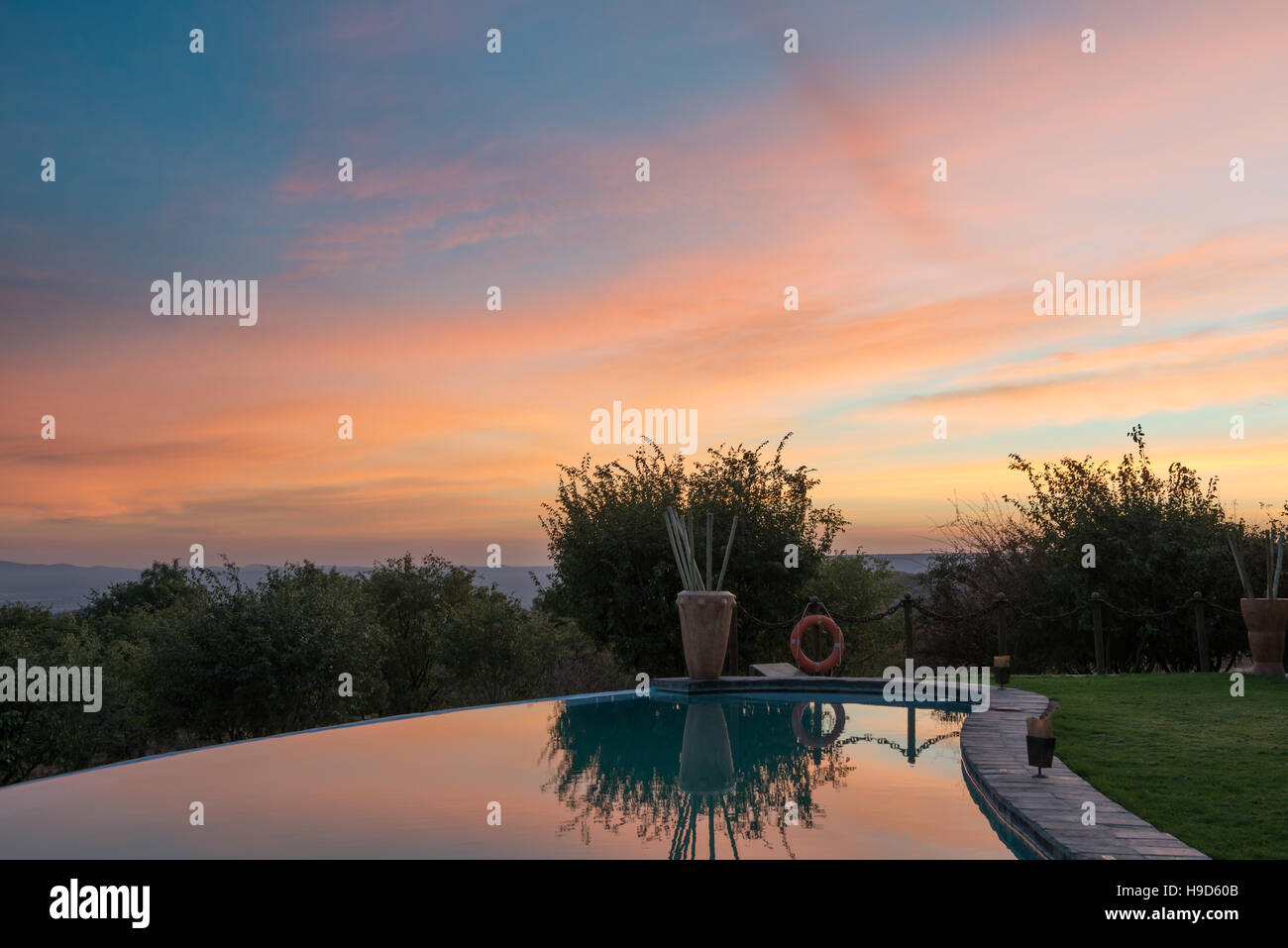 Matin nuages colorés et vert arbres namibien se reflètent dans un miroir d'une piscine de l'hôtel Banque D'Images