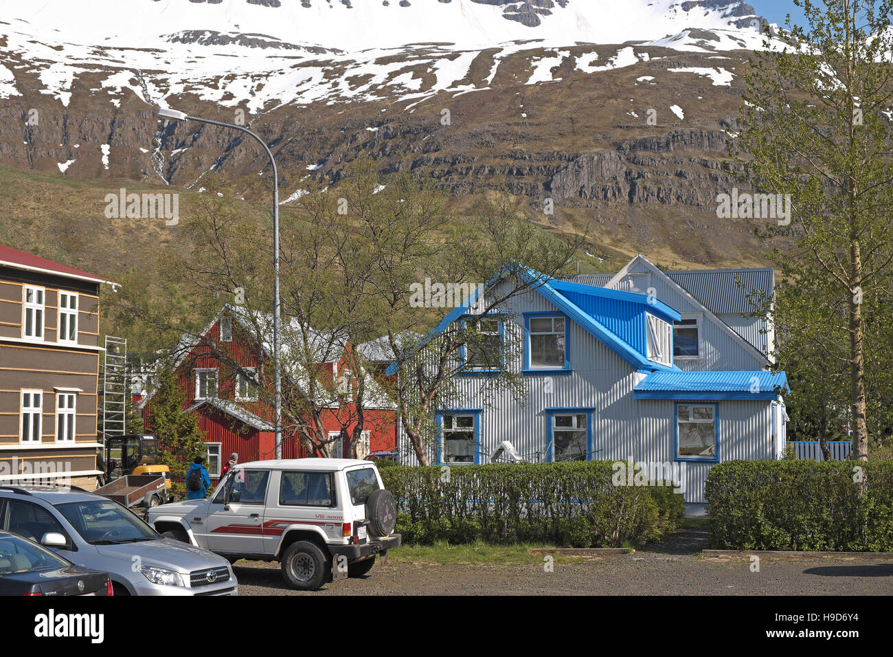 Maisons en bois peint de couleurs vives, Seydisfjordur, avec des montagnes enneigées au-delà, est de l'Islande. Banque D'Images