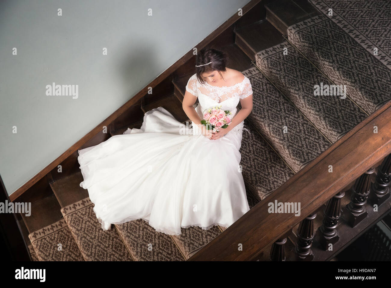 Mariée assise sur l'escalier avec sa robe de mariage se déploient en Banque D'Images