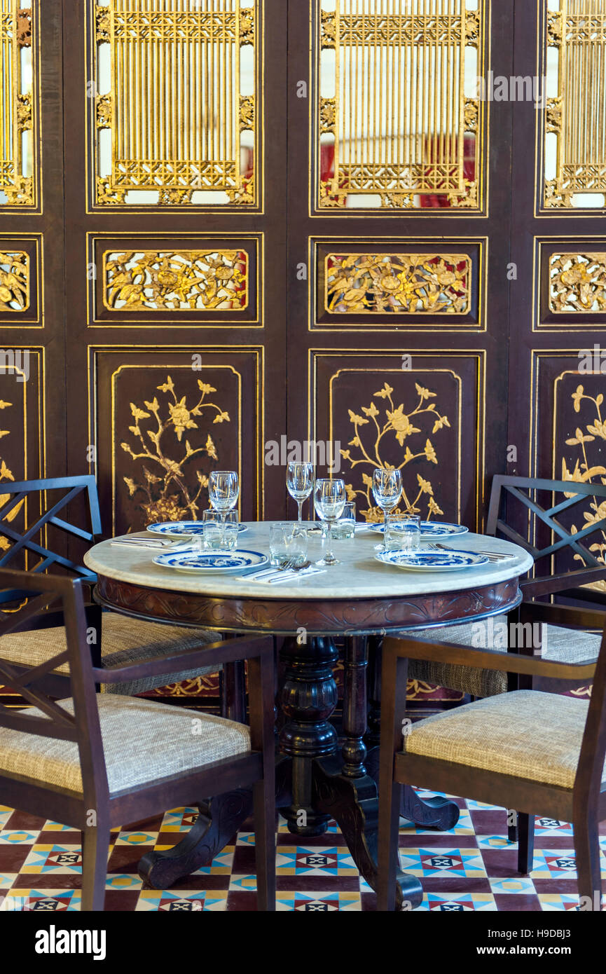 Une table de salle à manger en face d'un Chinois peranakan (Détroit) de la feuille d'or à l'écran au Restaurant Kebaya Sept Terrasses Hôtel à George Town, Penang, Malaysi Banque D'Images