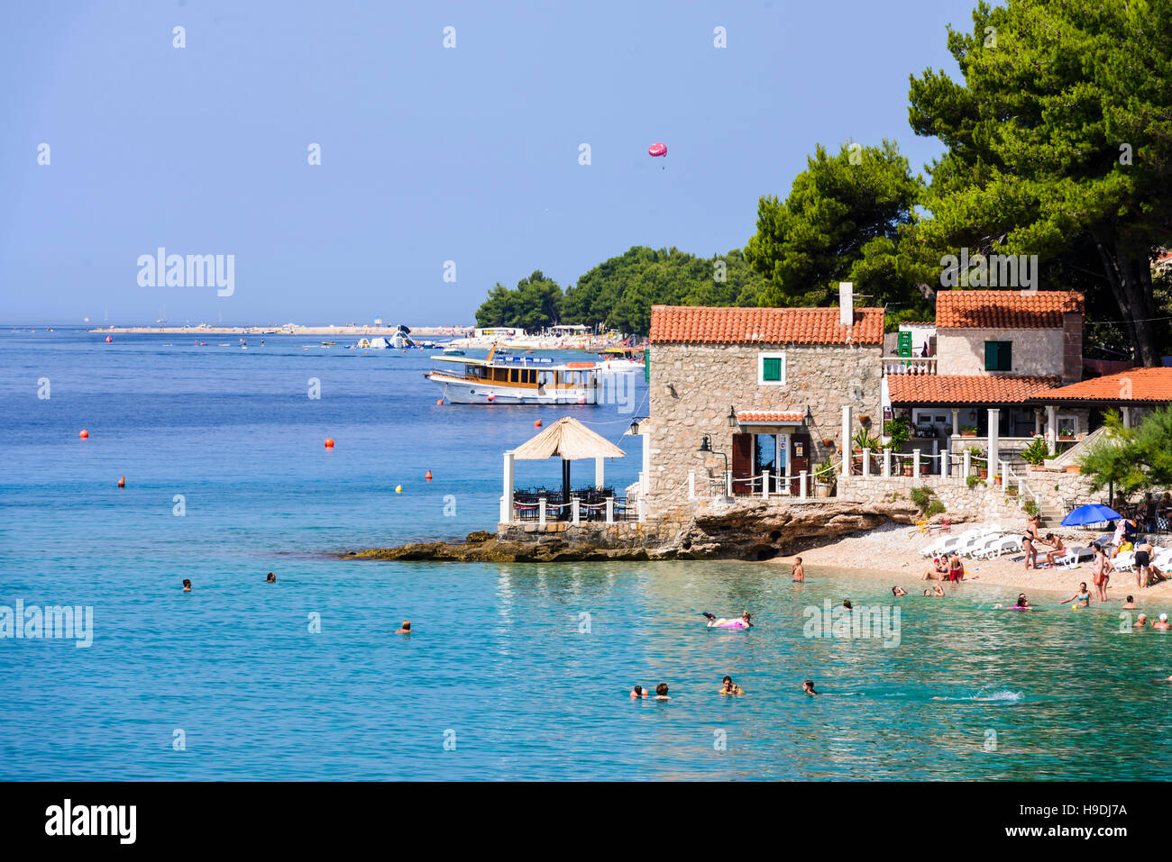 Bol, Croatie - 7 juillet 2016 : Beach Bar & Restaurant Ribarska kucica dans Bol, Île de Brac. Célèbre plage de Zlatni rat en arrière-plan Banque D'Images