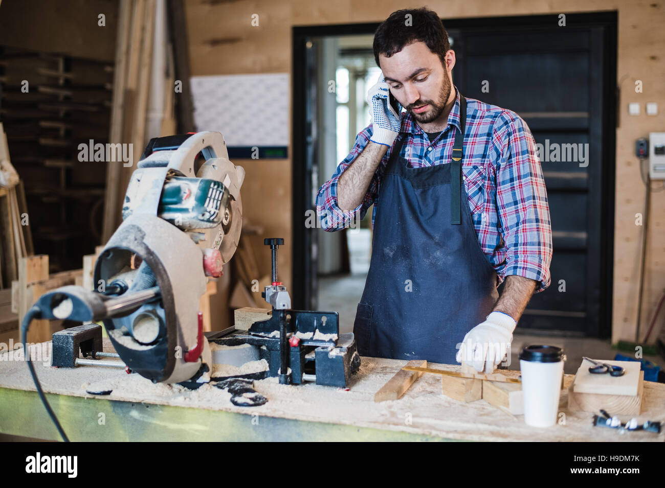 Portrait de carpenter appelant par téléphone intelligent à l'atelier Banque D'Images