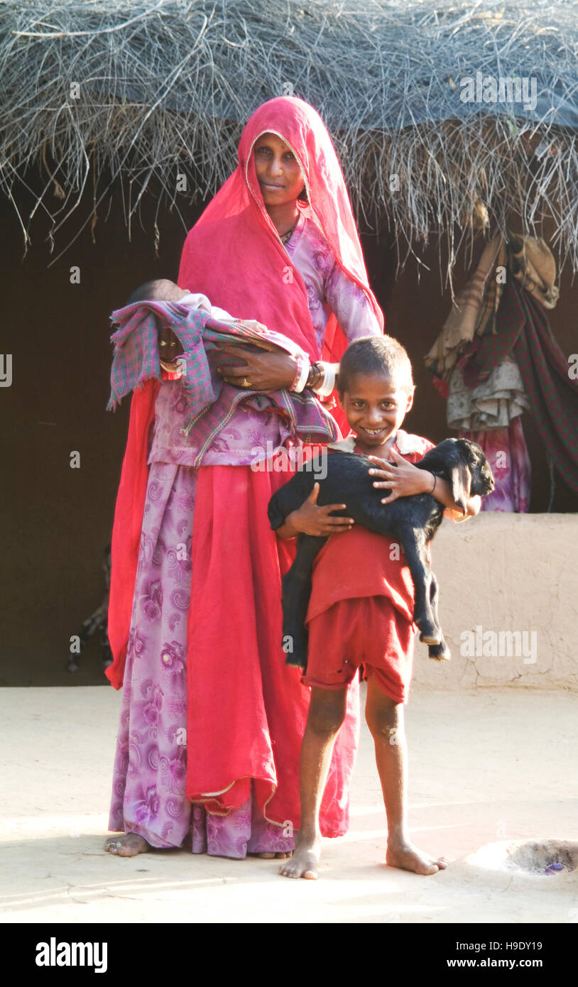 Une famille à l'extérieur de leur maison de terre dans les collines de Bhenswara, une petite communauté agricole à l'extérieur de Jodphur, Inde. Banque D'Images