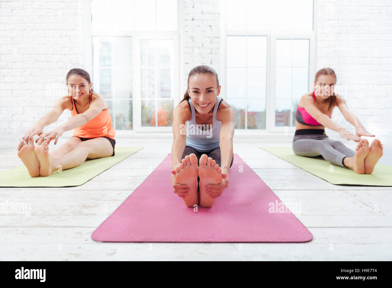 Trois filles de joie doing stretching in fitness studio Banque D'Images