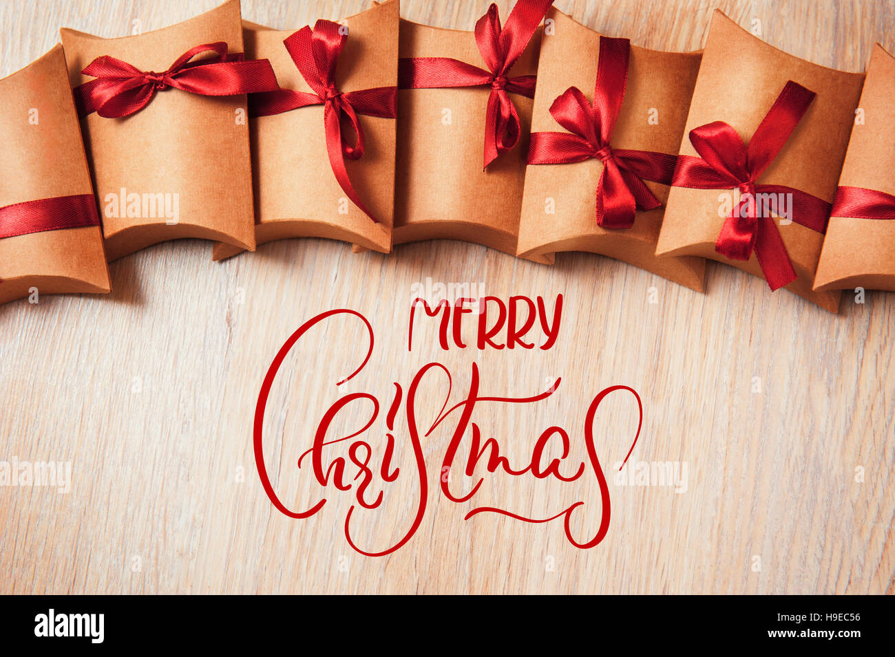 Boîte-cadeau enveloppé dans du papier kraft avec ribbon bow et le texte Joyeux Noël. Lettrage calligraphie Banque D'Images