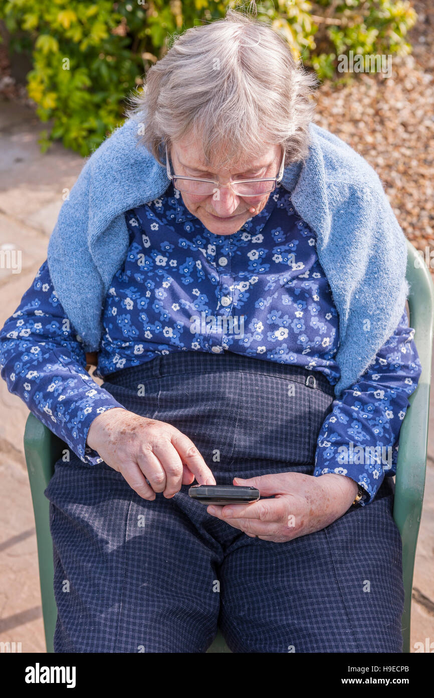 Une femme dans la 80's en utilisant un téléphone intelligent au Royaume-Uni Banque D'Images