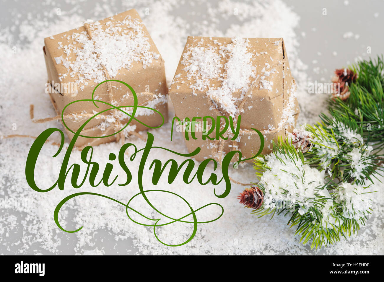 Boîtes cadeaux de papier kraft avec des branches d'épinettes et de texte Joyeux Noël. Lettrage calligraphie Banque D'Images