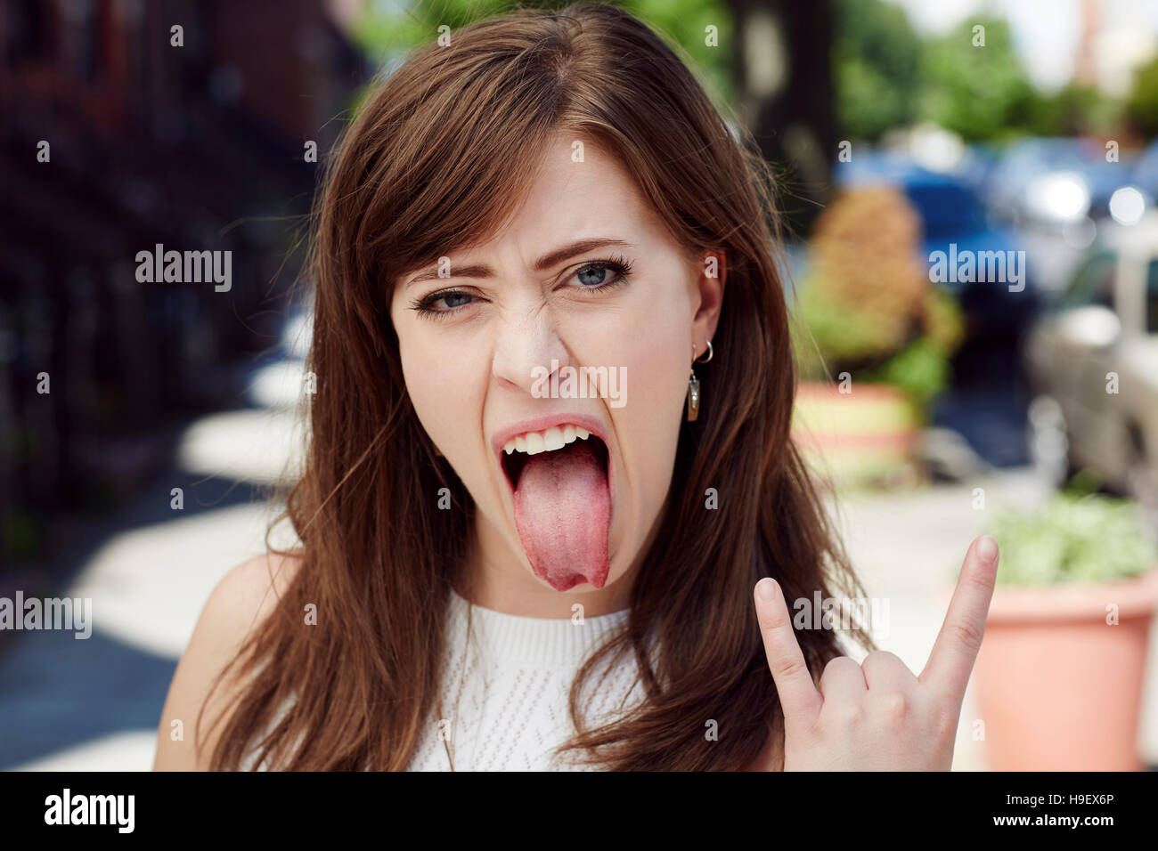 Vive Caucasian woman gesturing rock & roll in city Banque D'Images