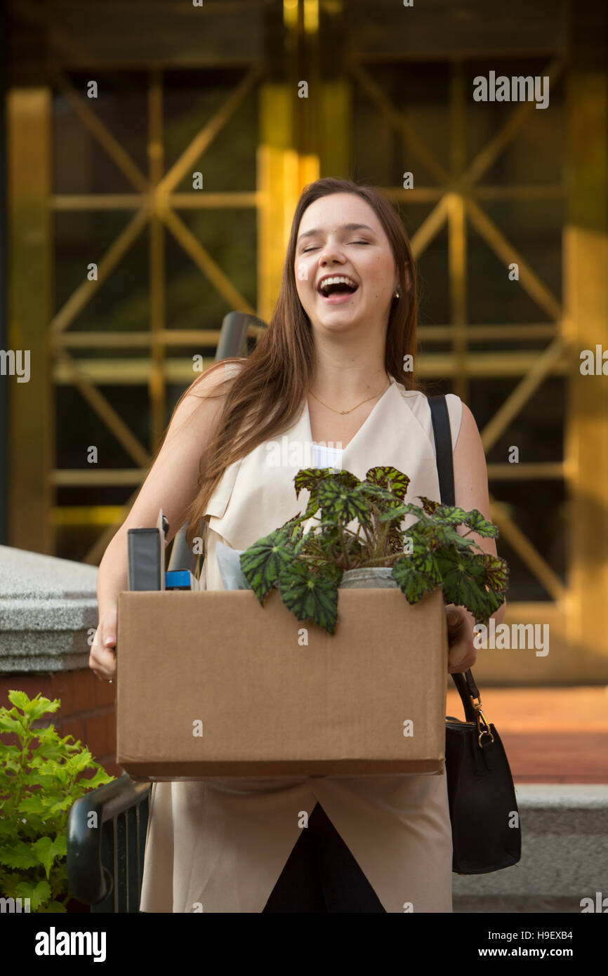 Laughing Woman carrying box avec des plantes en pot Banque D'Images