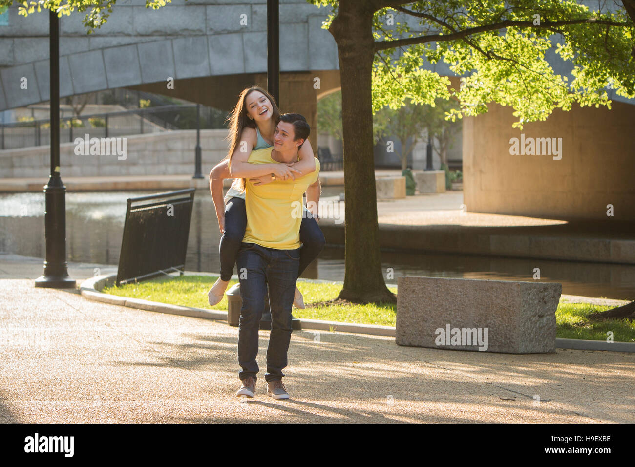 Caucasian man carrying girlfriend piggyback in park Banque D'Images