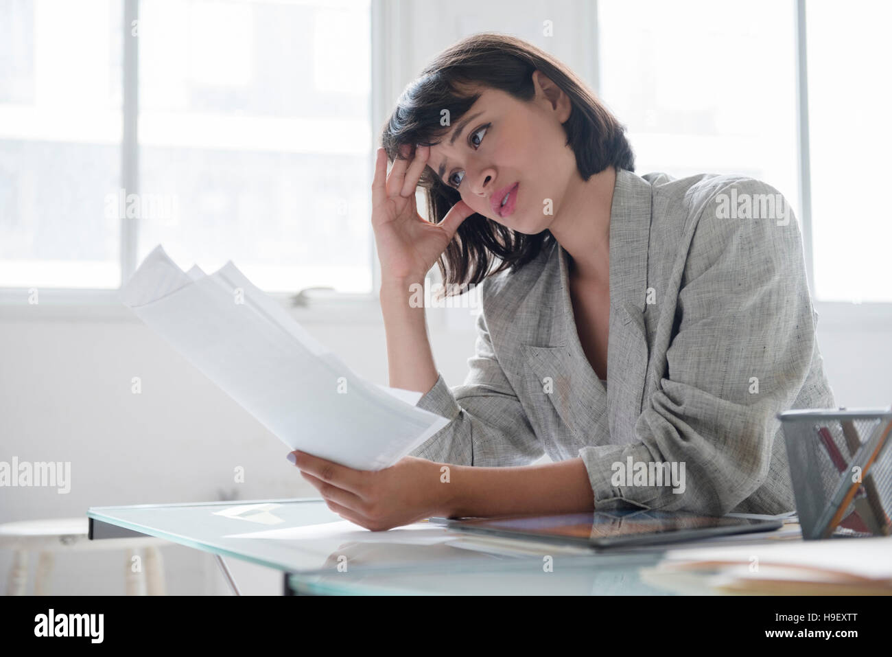 Hispanic businesswoman reading paperwork Banque D'Images