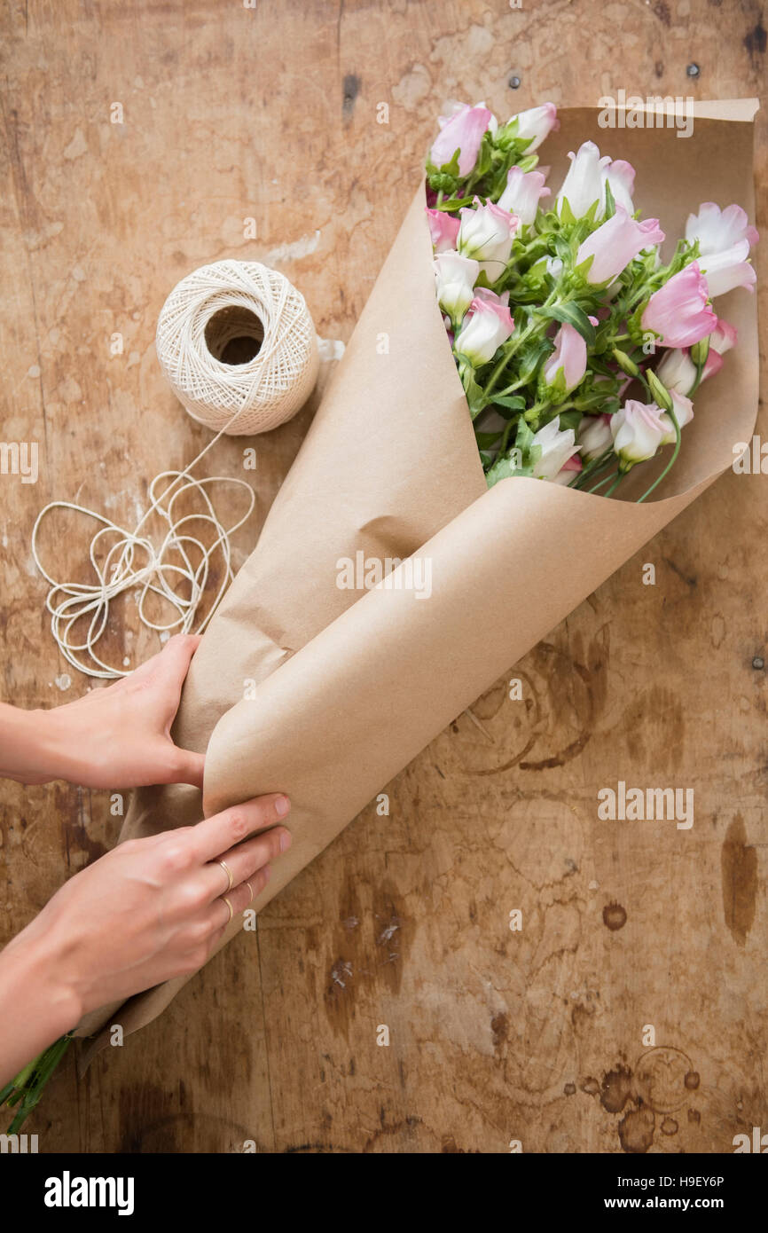 Mains d'Caucasian woman wrapping bouquet dans du papier brun Banque D'Images