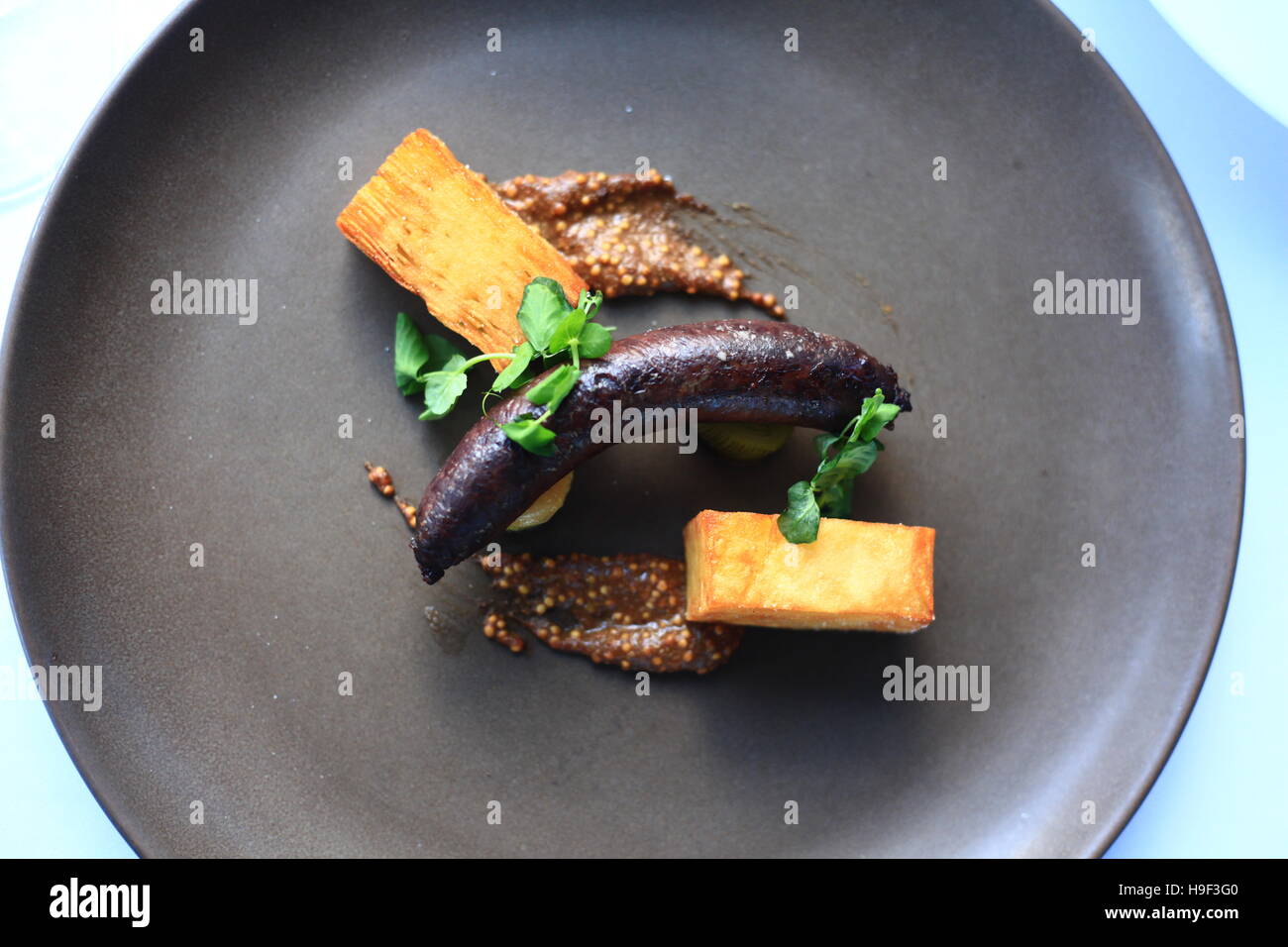 Boudin Noir saucisse avec mille feuille de pommes de terre, poireaux caramélisés et moutarde Banque D'Images