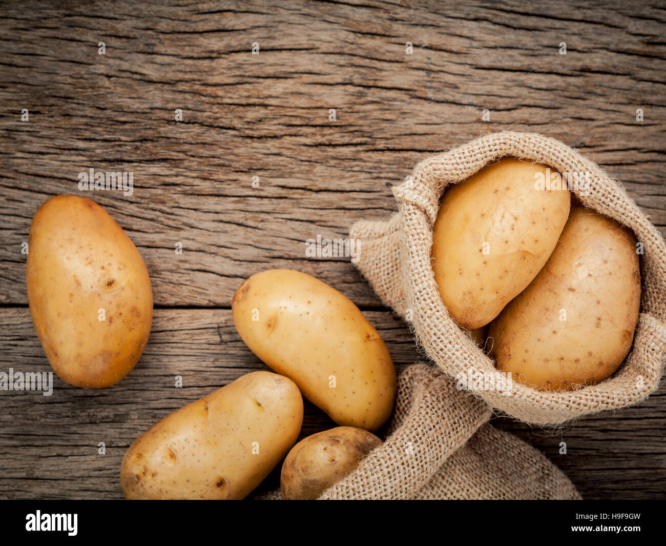 Des pommes de terre biologiques frais dans le chanvre nom sac sur rustique en background Banque D'Images