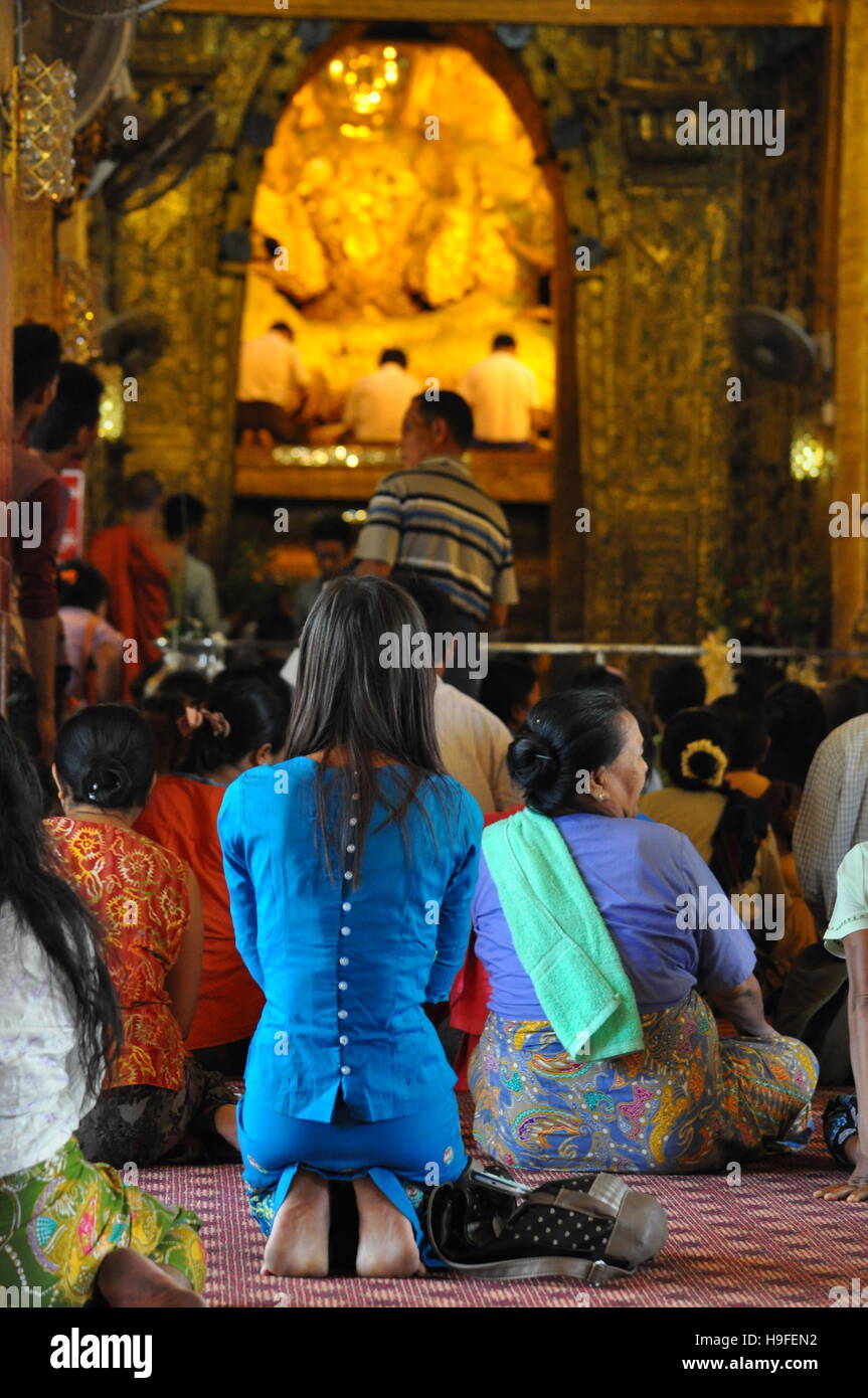 Fille priant dans la pagode Mahamuni en face de Bouddha en or sainte, Mandalay, Myanmar Banque D'Images