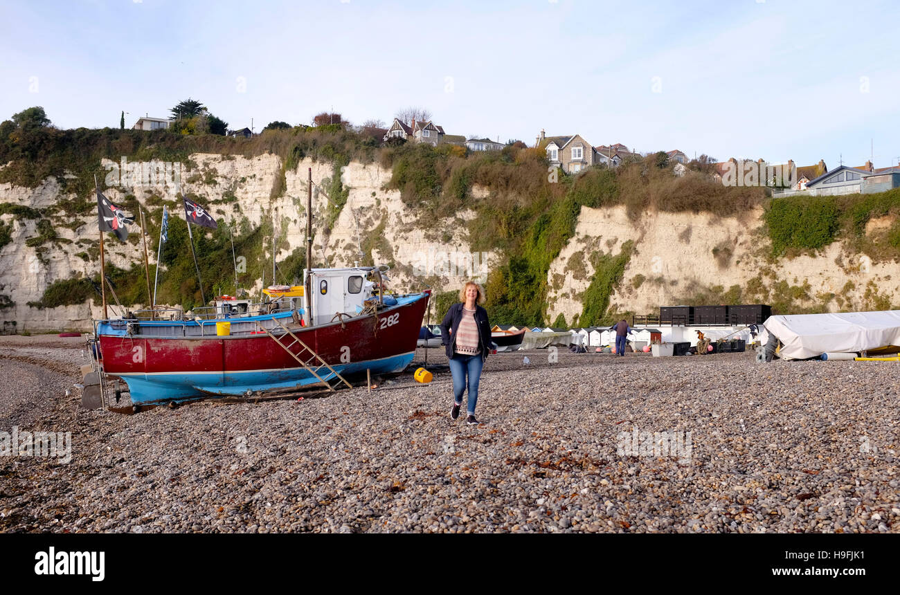 Femme marchant à bord de bateaux de pêche sur la plage de Beer Devon West Country UK Banque D'Images
